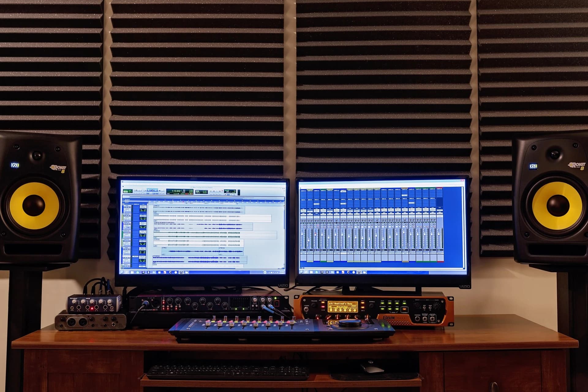 The control room: two monitors running Pro Tools between KRK Rokit 8 speakers, against acoustic foam