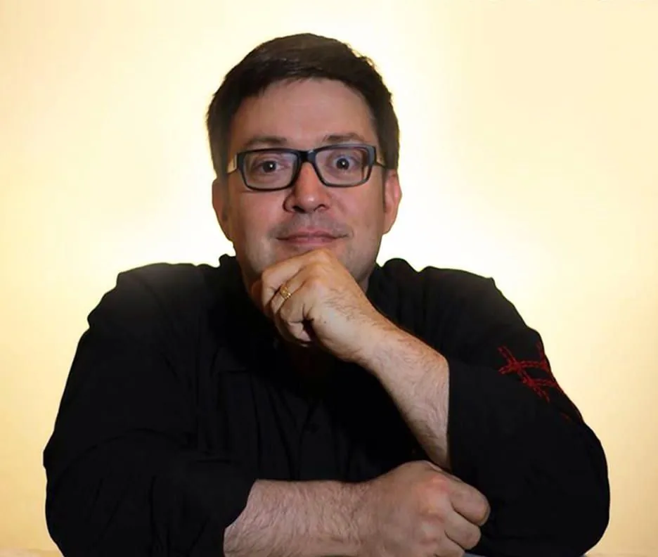 Portrait of Rob Novell in glasses and a black shirt, chin resting on his hand